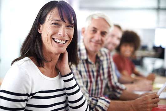 Smiling professionals in a meeting room, with a woman in focus, promoting psychology careers.