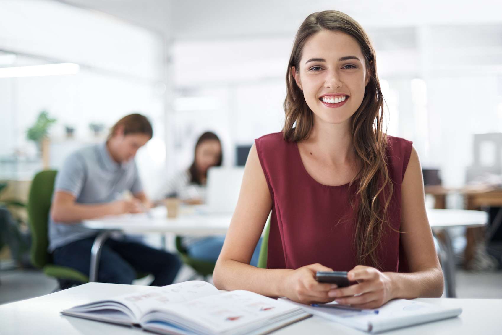 A female student sending a text on her cellphone while sitting with her textbooks